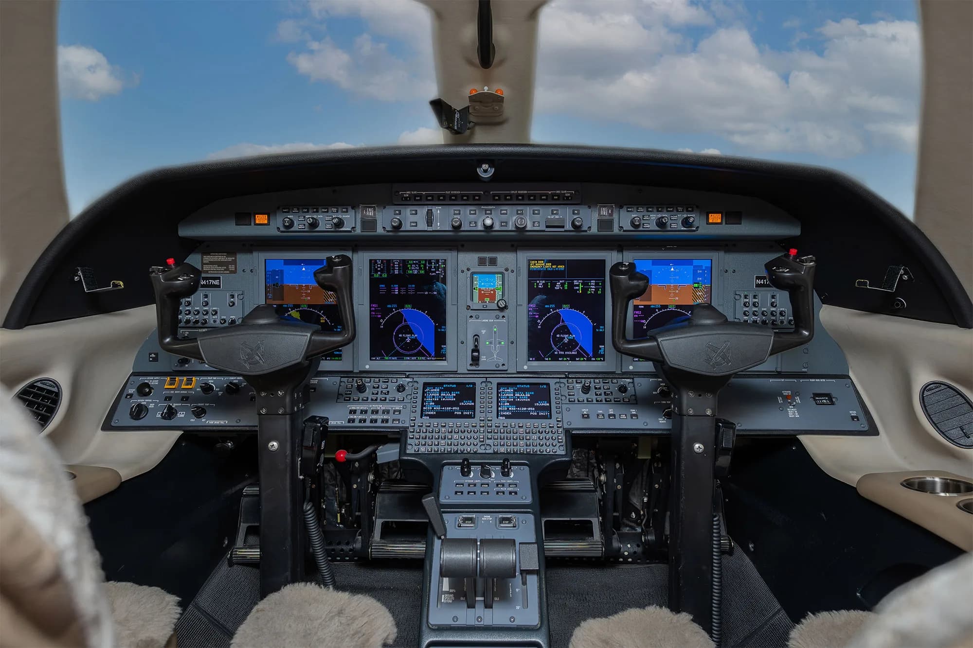 The cockpit of a business jet with multiple digital displays and control yokes.