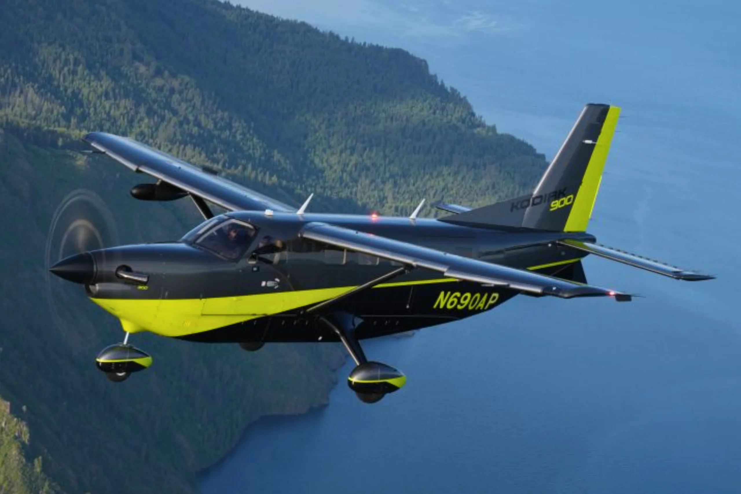A Kodiak 900 aircraft in flight with a black and yellow paint scheme.