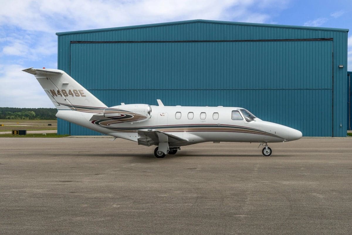 Side view of a Cessna Citation CJ1 parked in front of a hangar.