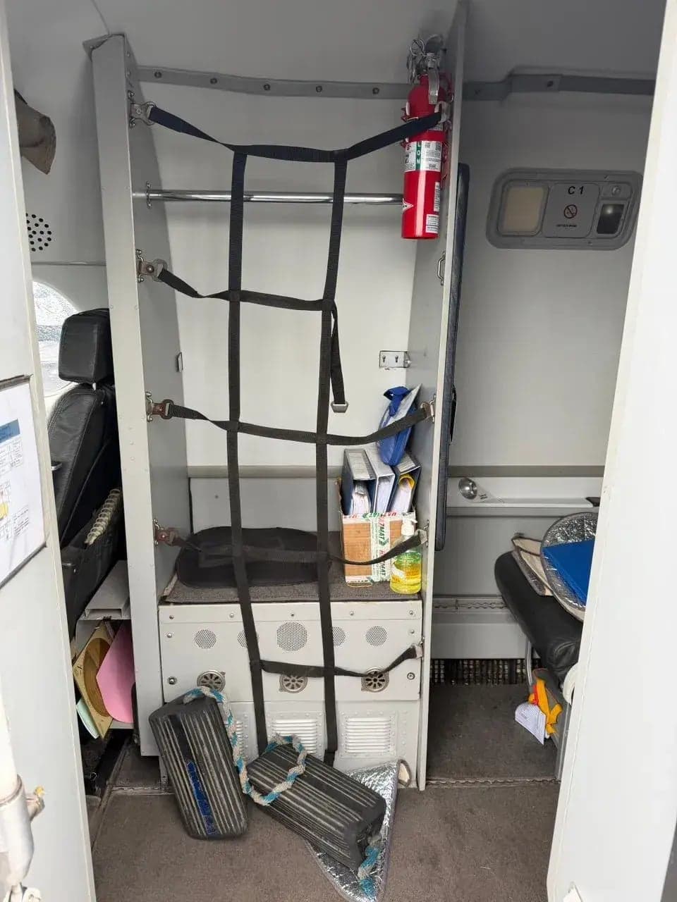 Interior view of the Beechcraft 1900 cabin with storage and emergency equipment.
