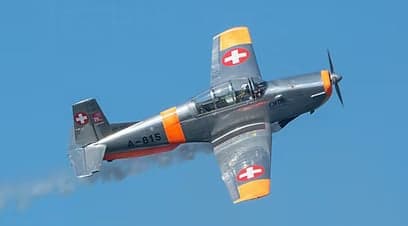 Pilatus PC-7 on the ground with orange and silver paint scheme.
