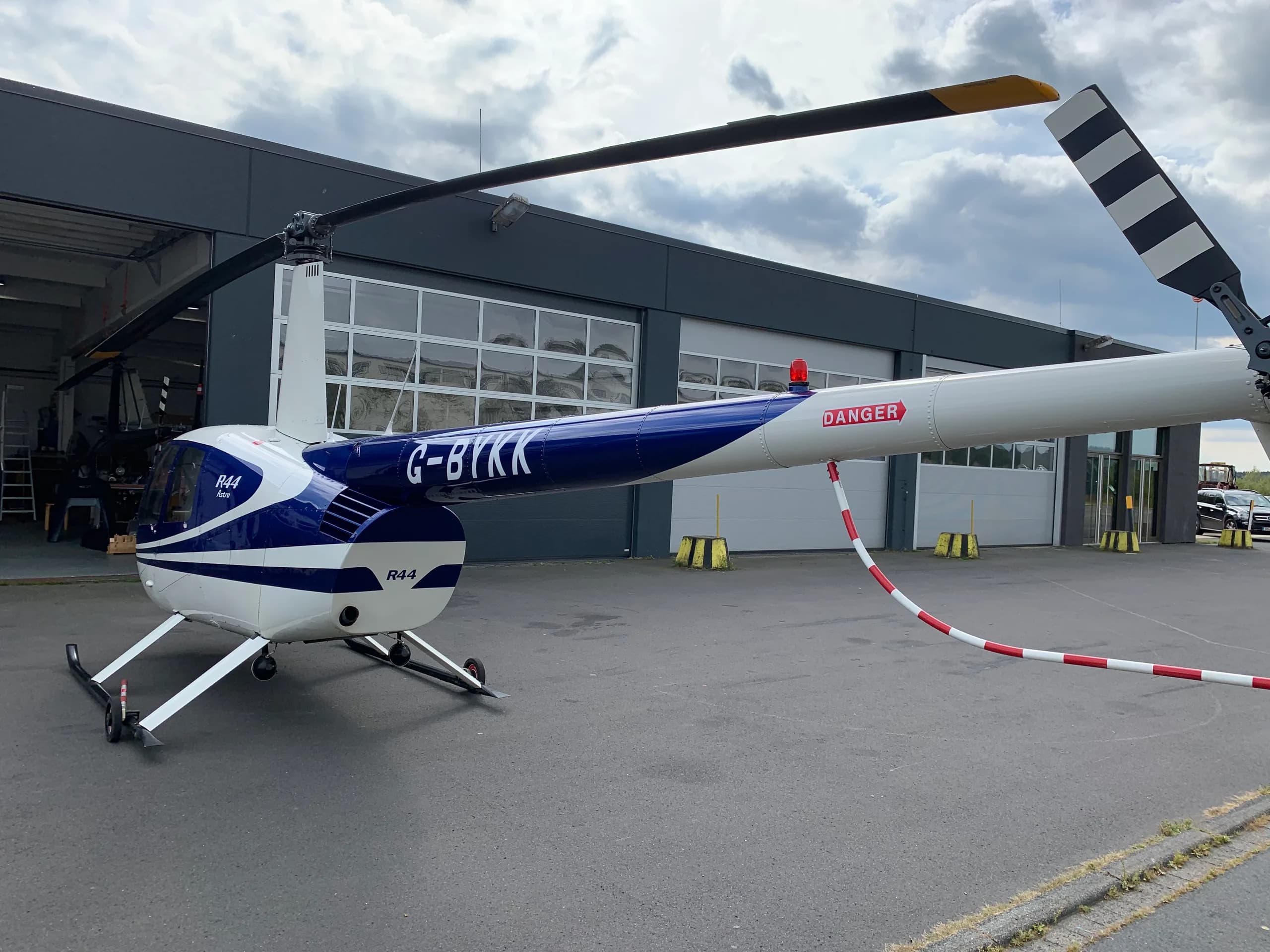 Side view of a Robinson R44 Raven with blue and white paint scheme at an airport.