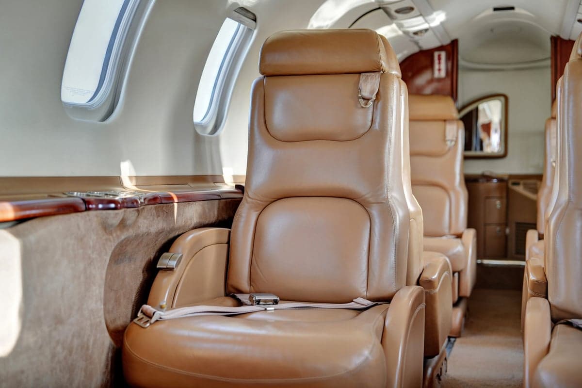 View of the aircraft cabin with a wooden table and tan leather seats.