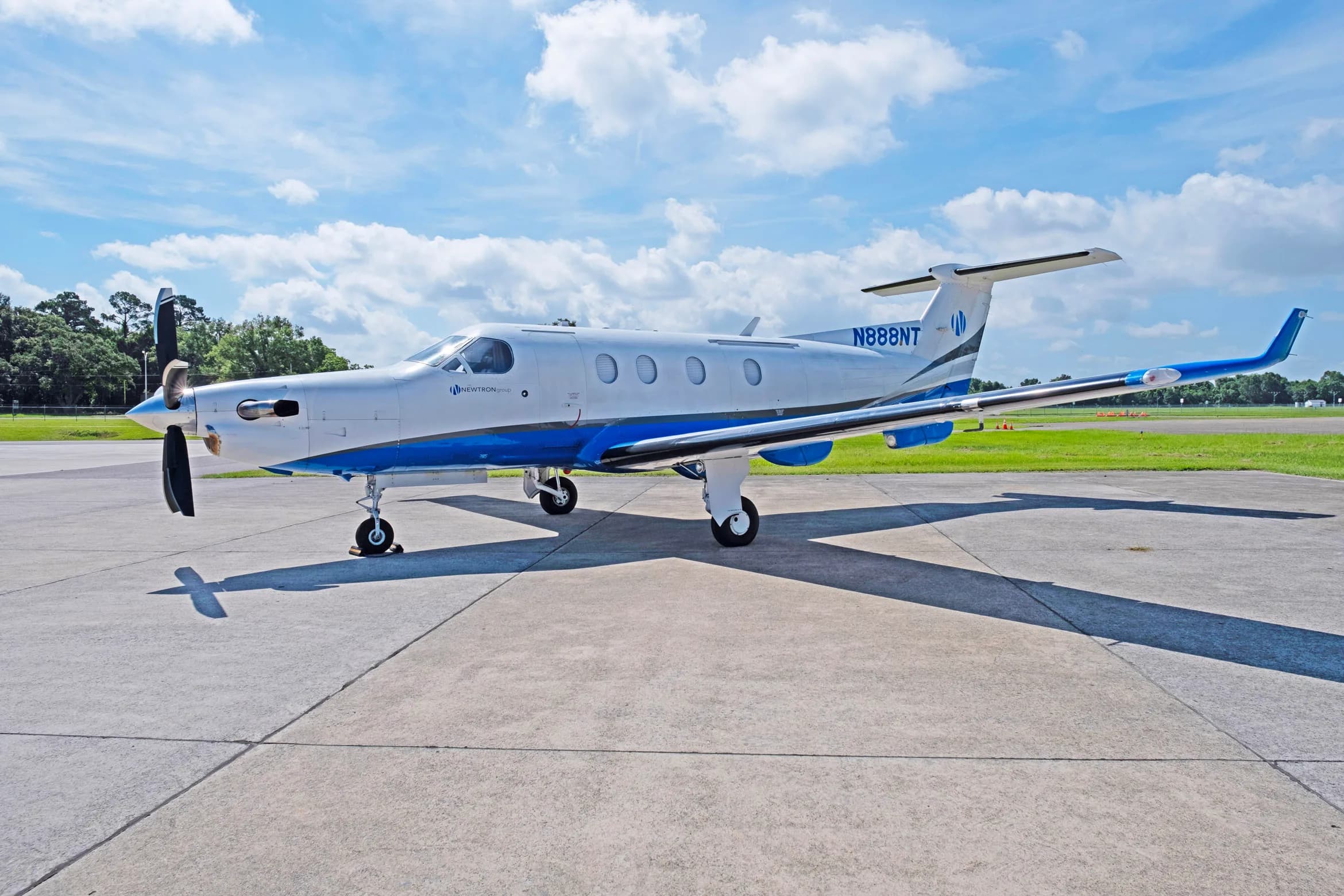 A white and blue Pilatus PC-12 aircraft, tail number N888NT, parked on a tarmac with a slight side view.