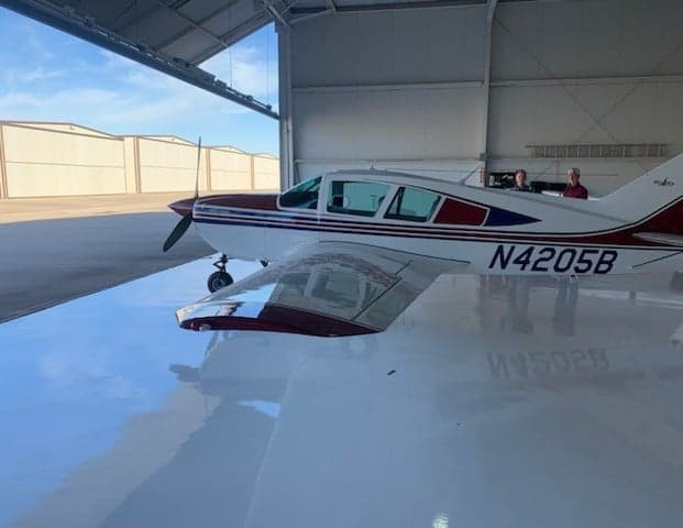 Side view of N4205B aircraft in a hangar with people in the background.