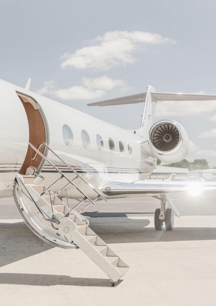 A white jet aircraft is shown with the boarding stairs extended.