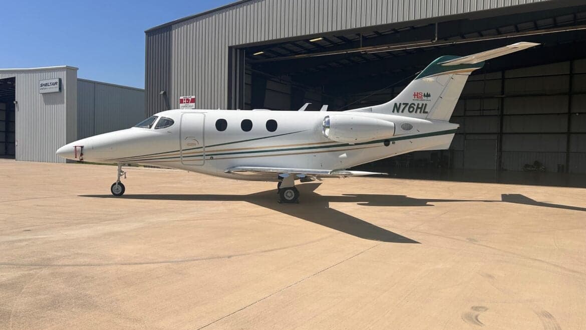 Side view of the N76HL Premier I aircraft in front of a hangar.
