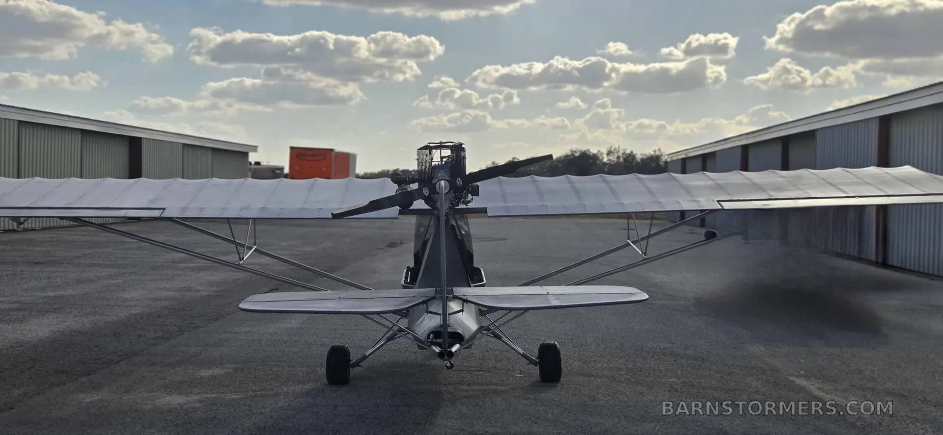 A frontal view of a gray aircraft with a propeller.