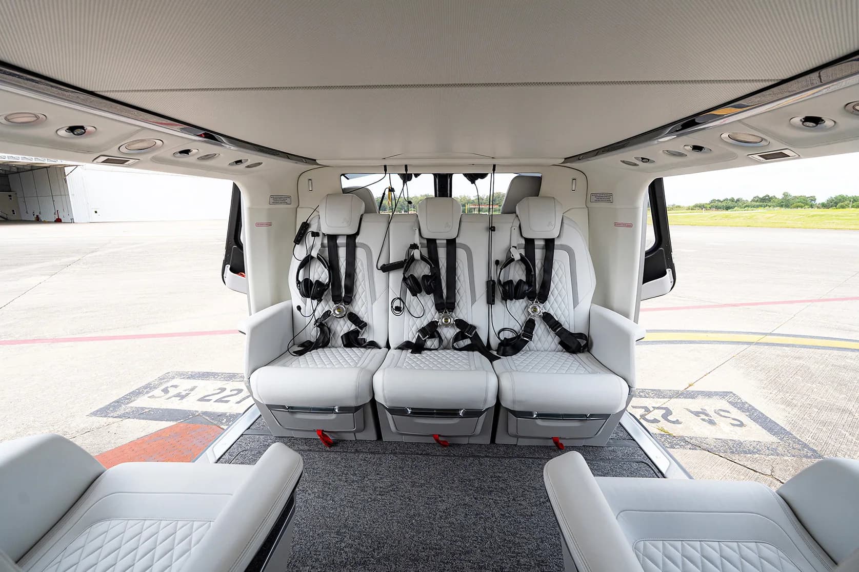 View of the helicopter's interior with white leather seats and headsets.
