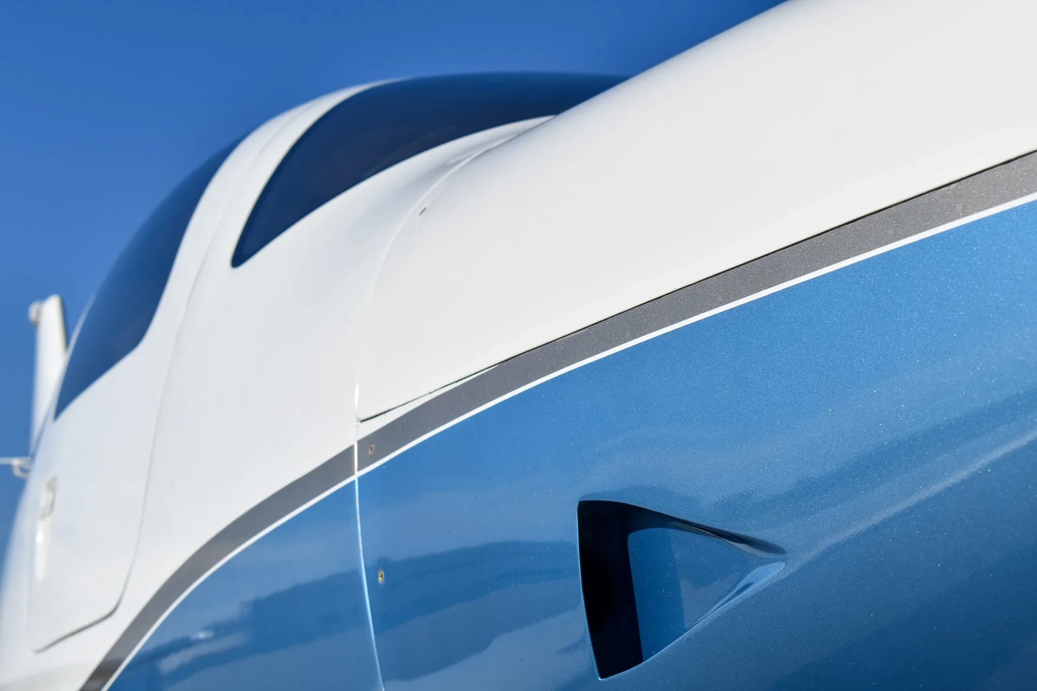 A close-up detail of the white and metallic blue paint scheme on the aircraft's fuselage.