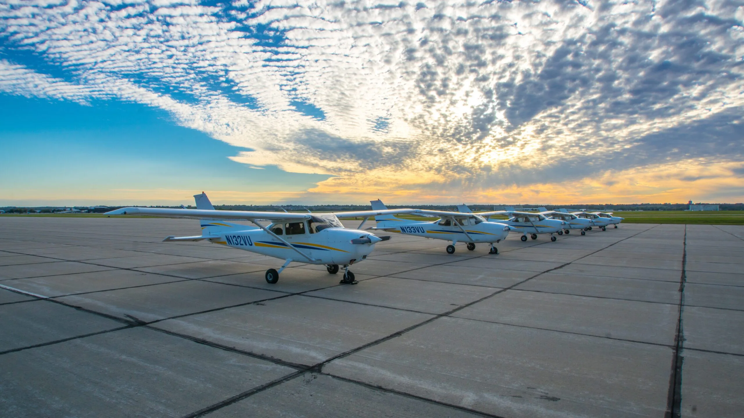 Line of Cessna 172 aircraft on the ramp at sunset.