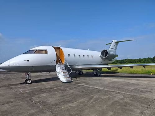 A Challenger aircraft is parked on the tarmac with the door and stairs open.