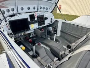 View of the aircraft cockpit with instrument panel and gray seats.