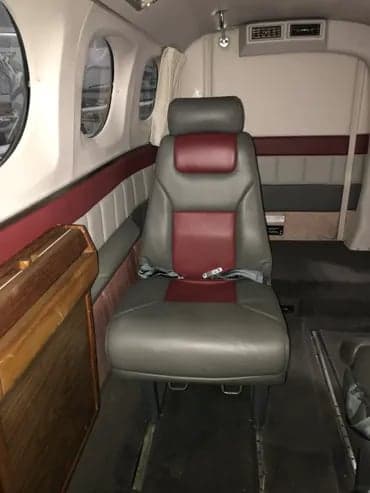 A single gray and maroon leather seat is shown inside the aircraft cabin.