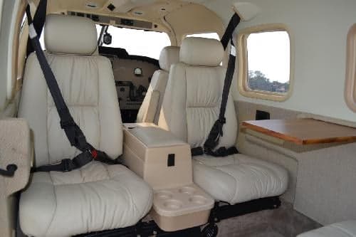 The interior of the aircraft features cream-colored leather seats and a small table.