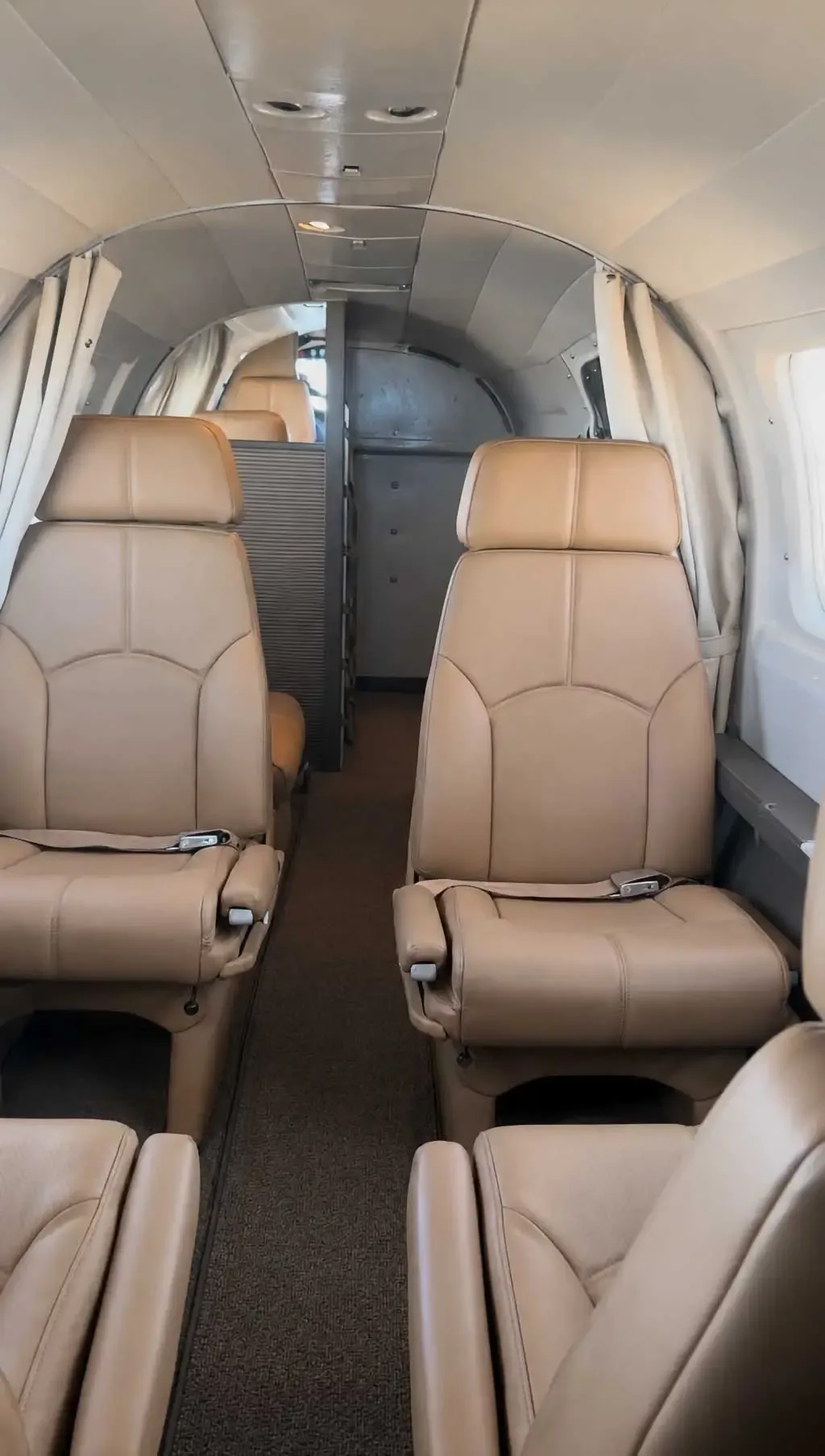The interior cabin of the aircraft with rows of tan leather seats.