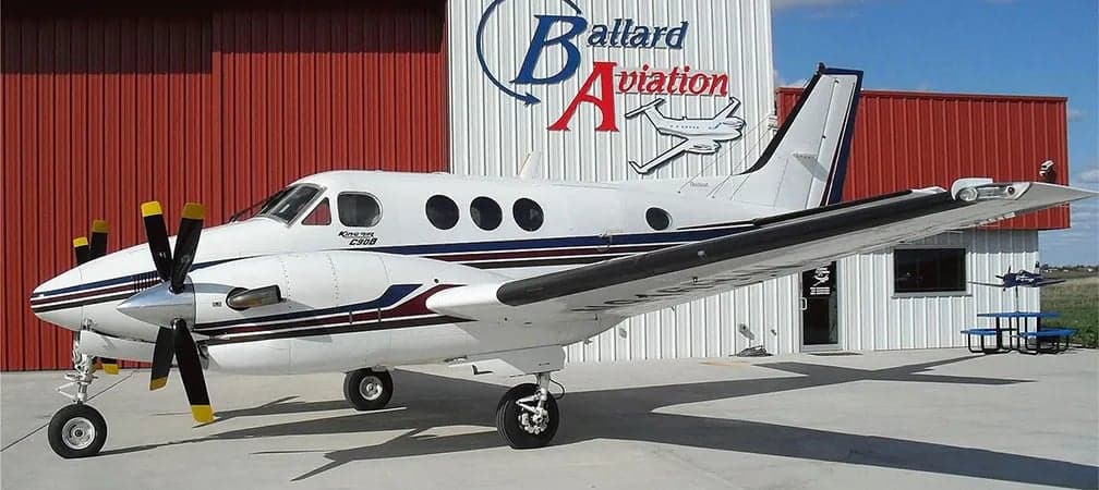 King Air C90B parked in front of Ballard Aviation hangar.