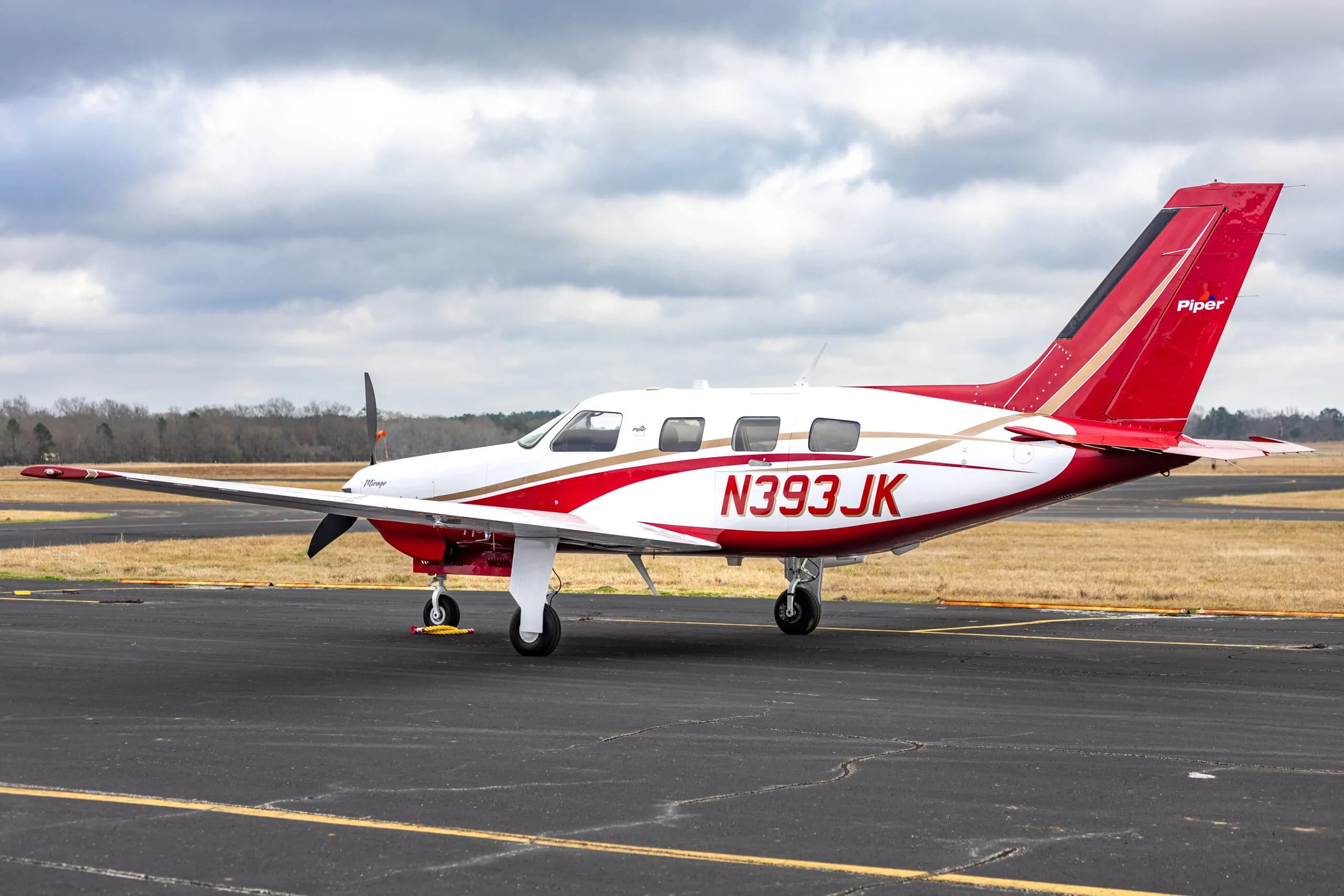 Piper Mirage N393JK on the tarmac, showcasing its red and white exterior.