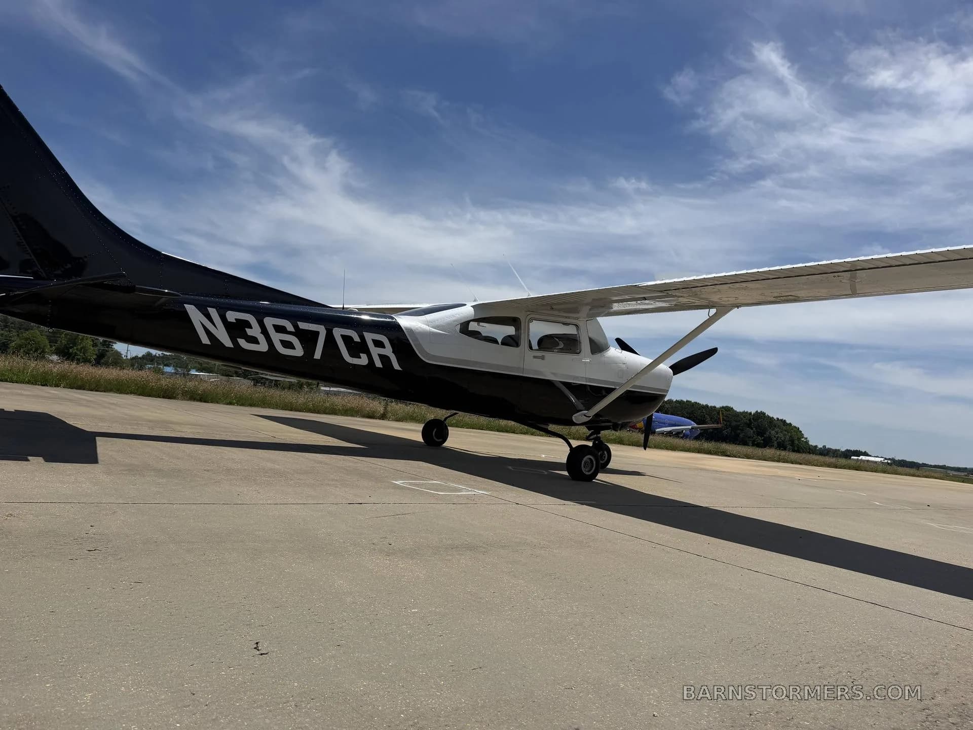 A black and white Cessna 182 Skylane (N367CR) parked on an asphalt ramp, viewed from the rear-left.