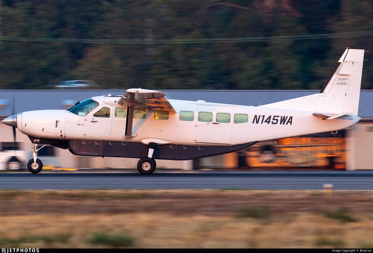 Side view of a white Cessna 208 Caravan taxiing on the runway.