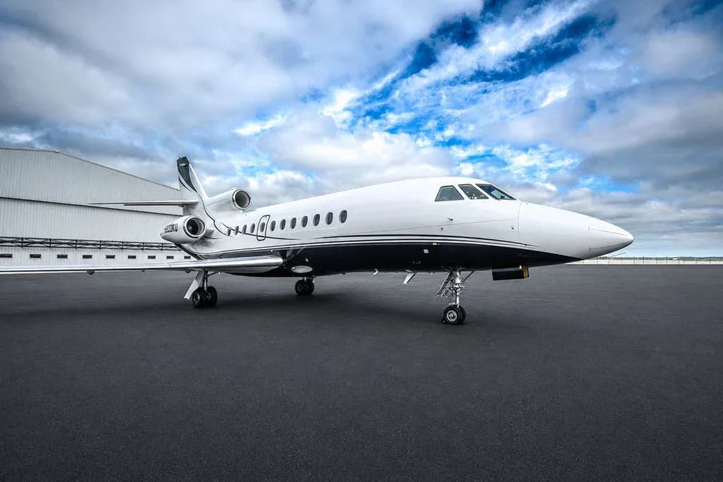 A Dassault Falcon 900EX business jet, registration N900KU, parked on a tarmac in front of a hangar.