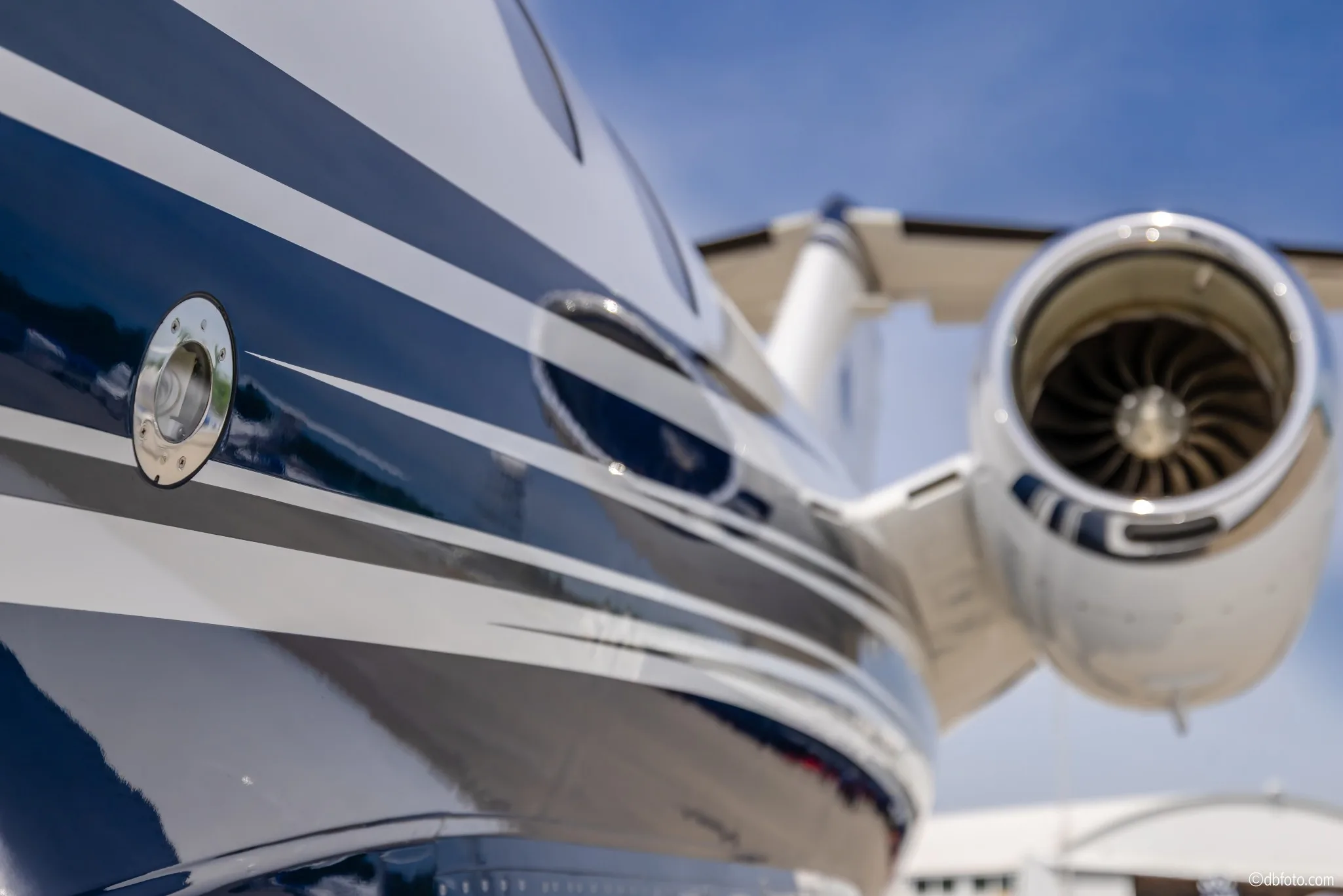 A close-up view of the blue and white striped fuselage and engine of a Cessna Citation CJ3 business jet.