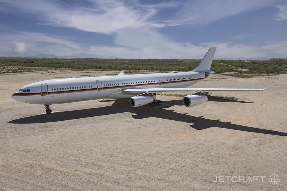 An aerial view of a white Airbus A340-300 with a German government livery parked on a desert airfield.
