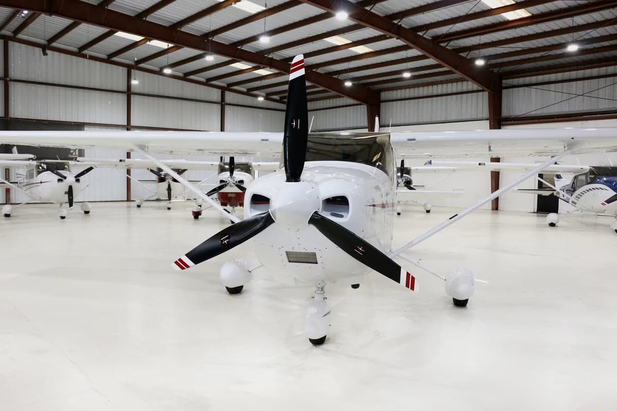 Front view of a Cessna aircraft with a white paint scheme in a hangar.