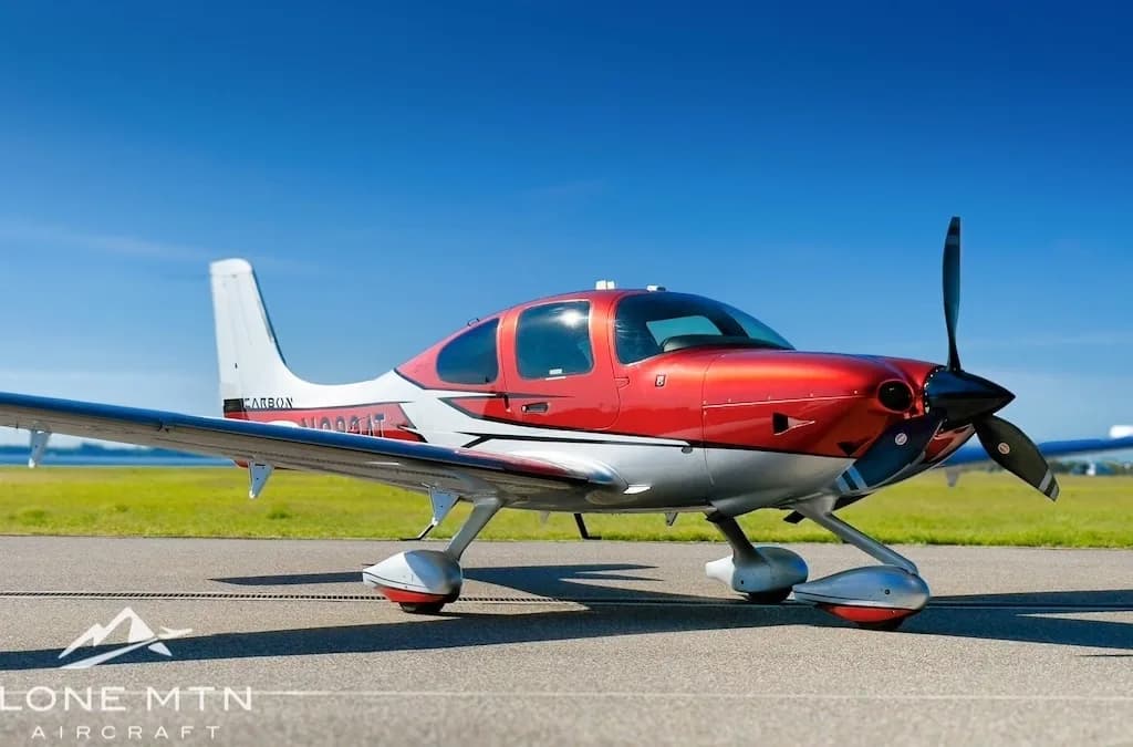 A low-angle view of a red and silver Cirrus SR22T aircraft, registration N282AT, parked on an tarmac under a clear blue sky.