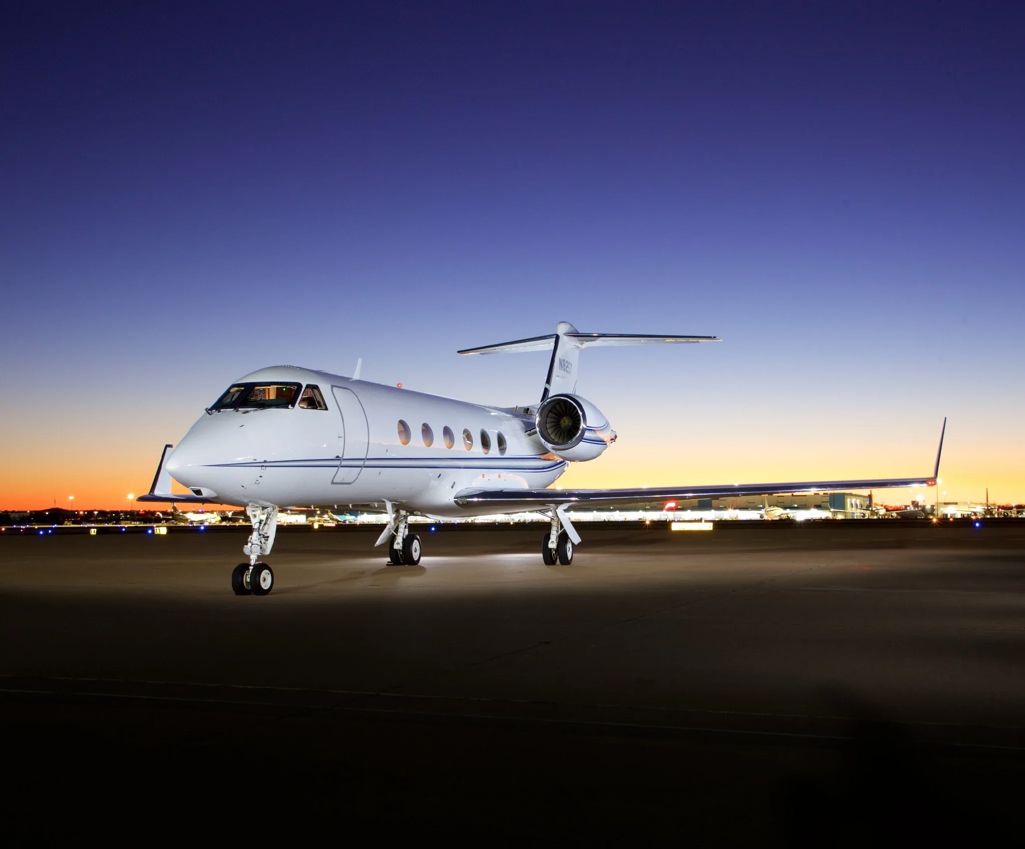 A white Gulfstream G550 aircraft, registration N819VD, is parked on an airport tarmac at dusk.