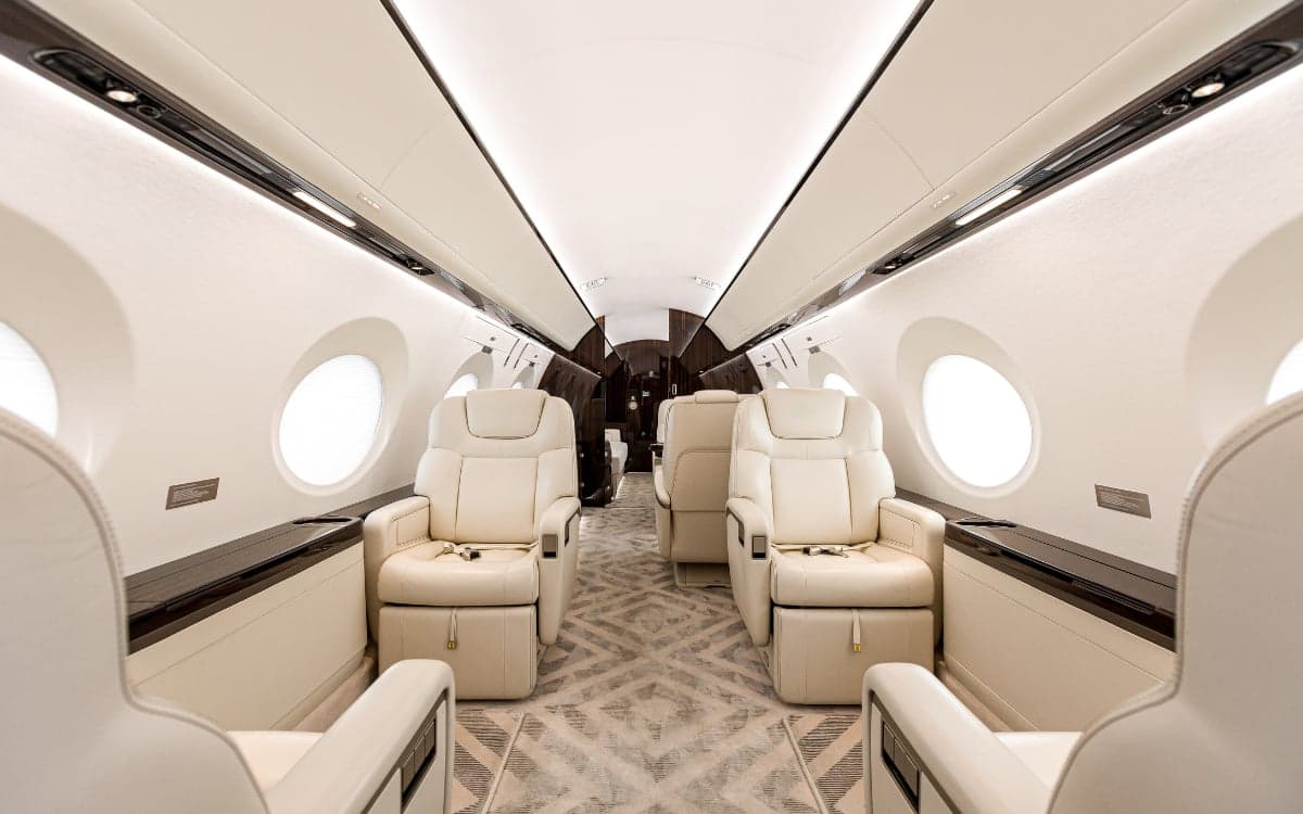 A view down the aisle of the Gulfstream G500 cabin featuring cream-colored leather seats.