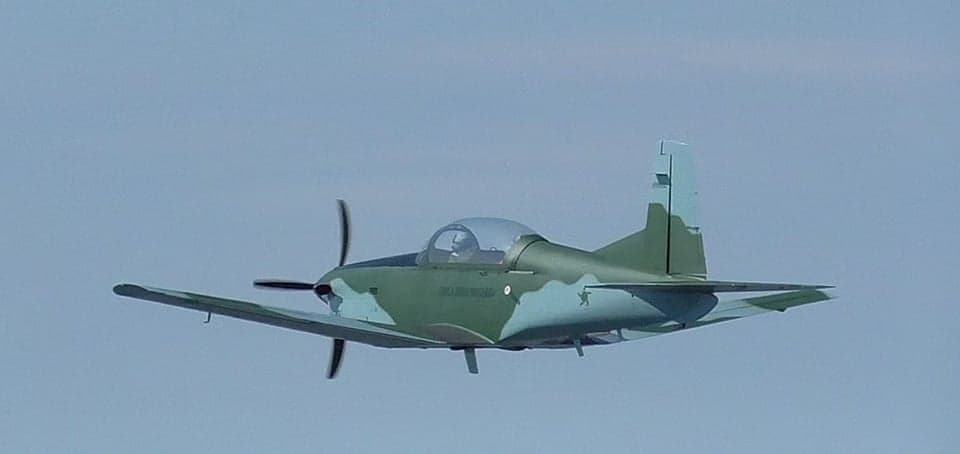 A Tucano aircraft in flight with a camouflage paint scheme.