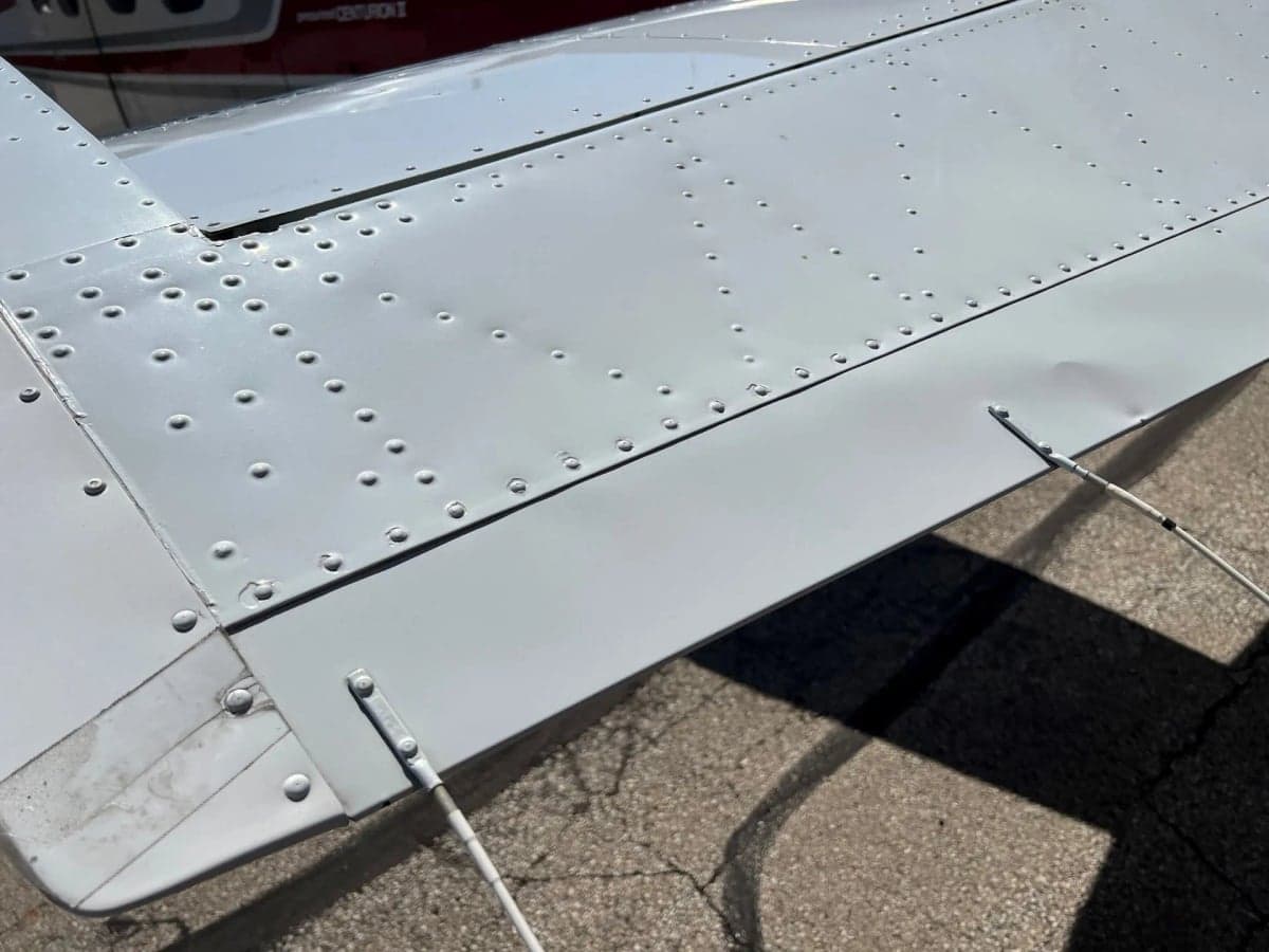Close-up view of the riveted surface of an aircraft's white wing and flap.