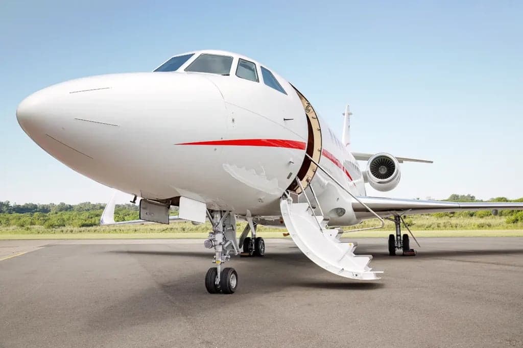 A Falcon aircraft with the airstair door open on the tarmac.