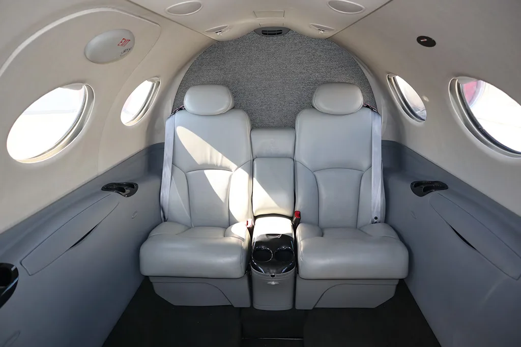 The light gray leather seats in the rear cabin of a private jet, seen from a wider angle.