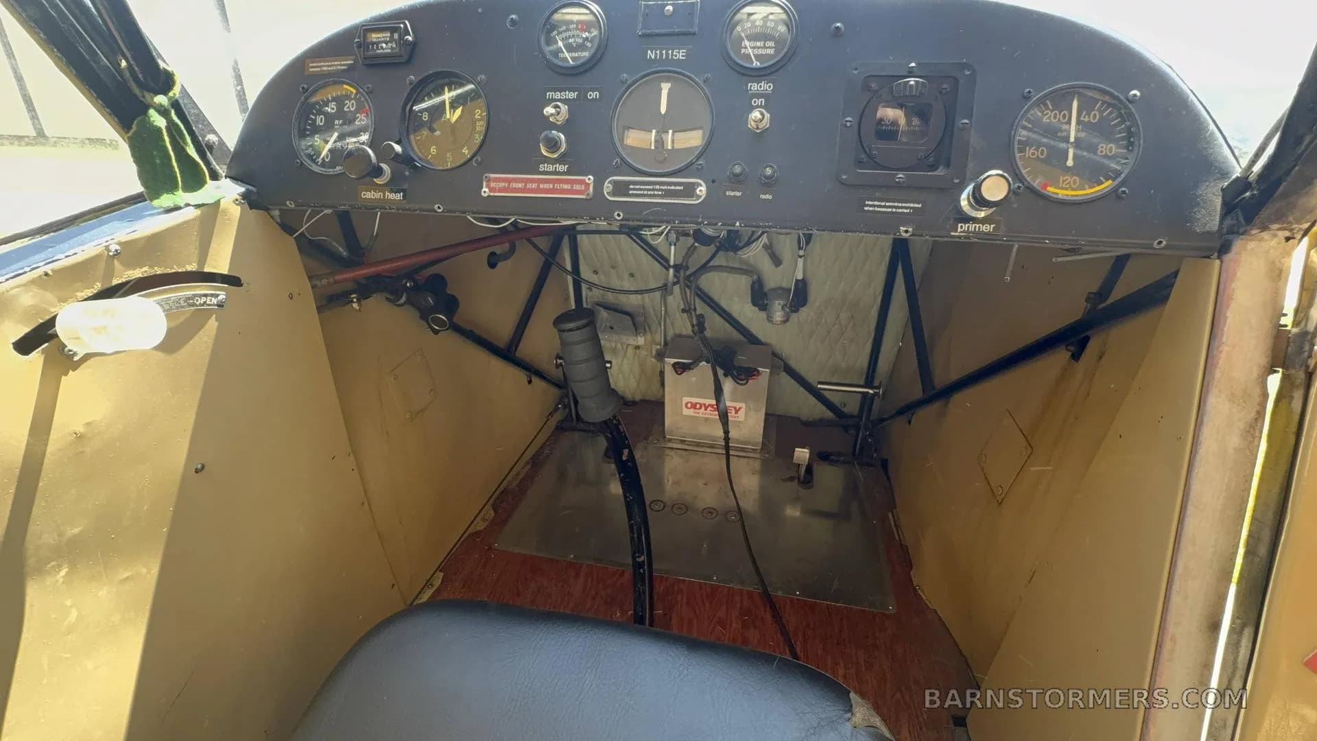 The cockpit of the aircraft, showing the instrument panel with gauges, controls, and a single seat.