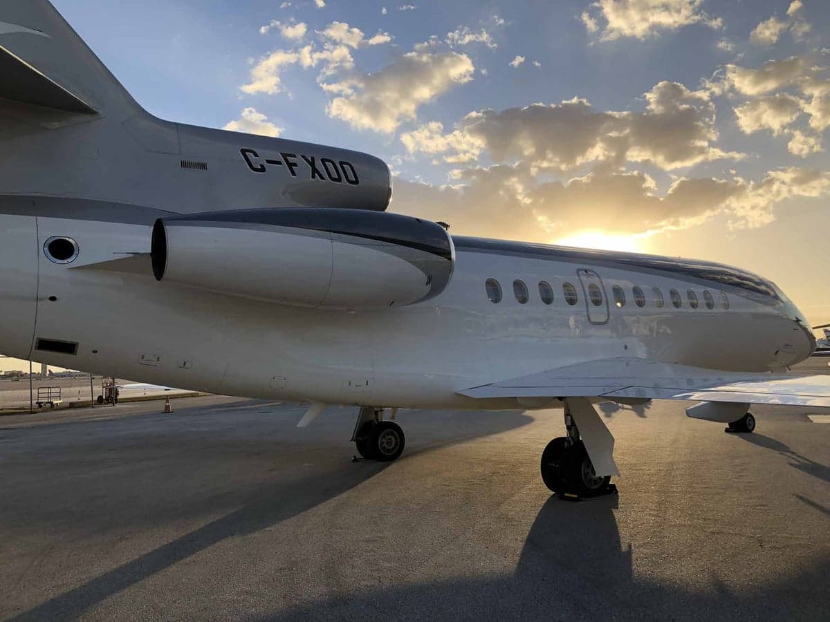 Close-up of the tail section of the C-FXOO aircraft on the tarmac at sunset.