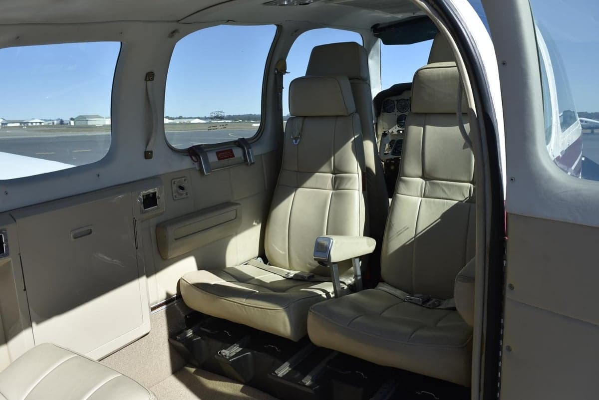 The beige leather interior of a small aircraft cabin with two rows of seats.