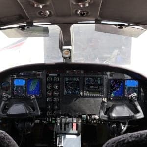Aircraft interior with black leather seats and diamond stitching.