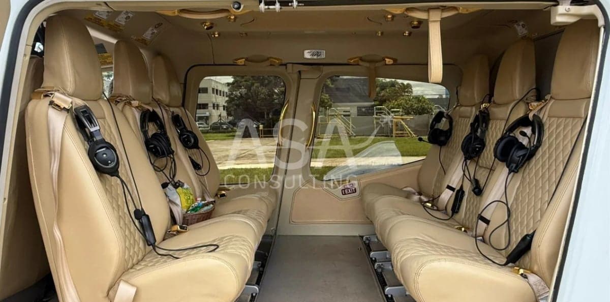 The interior of a helicopter with tan leather seats and headsets.