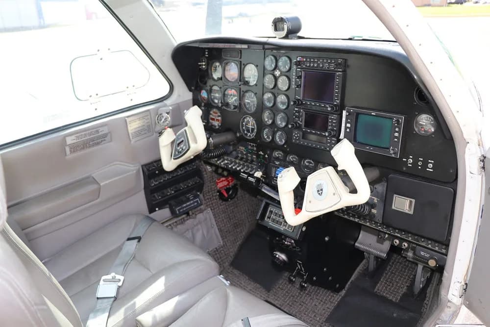 The cockpit of a Beechcraft Baron 58, featuring a modern instrument panel with multiple displays and two control yokes.