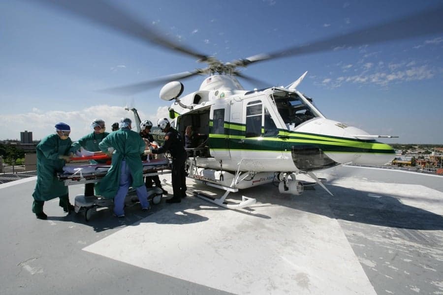Helicopter on a helipad with medical personnel transferring a patient.