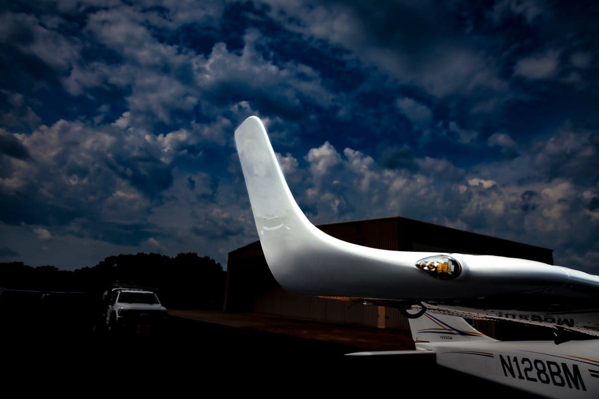 The tail of a Tecnam P2006T with registration N128BM is shown against a cloudy sky.