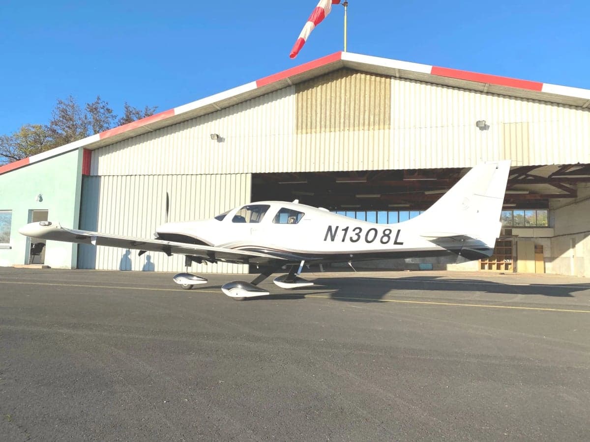 A Cirrus Columbia 400, registration N1038L, parked on the tarmac with its doors open.