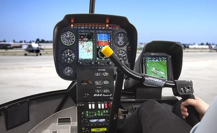 Cockpit view of a Robinson R44 helicopter with modern avionics.