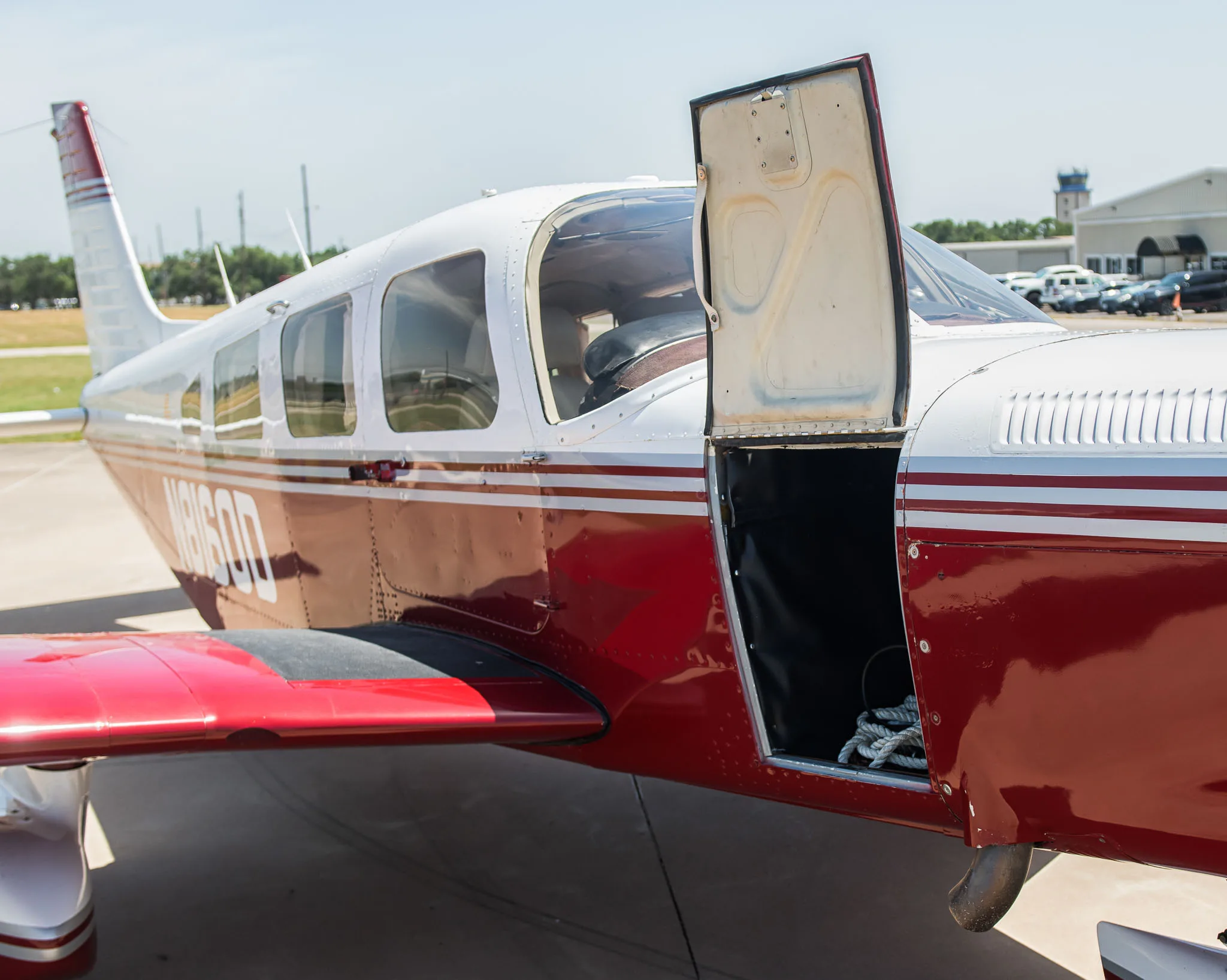 The red and white aircraft N8160D with its main cabin door open, revealing the interior.