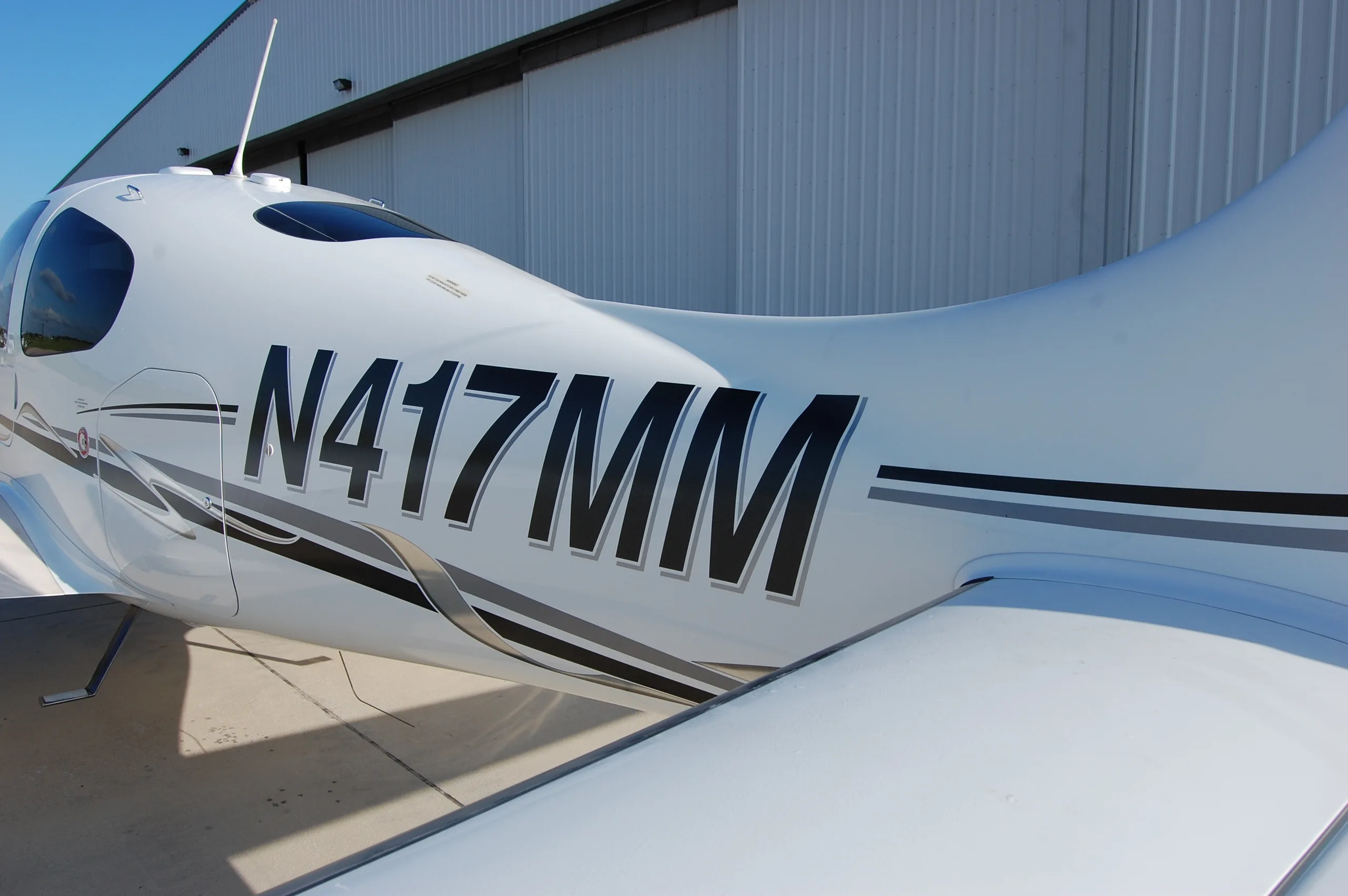 A close-up view of the fuselage of the Cirrus SR22 aircraft showing the registration N417MM and its paint scheme.