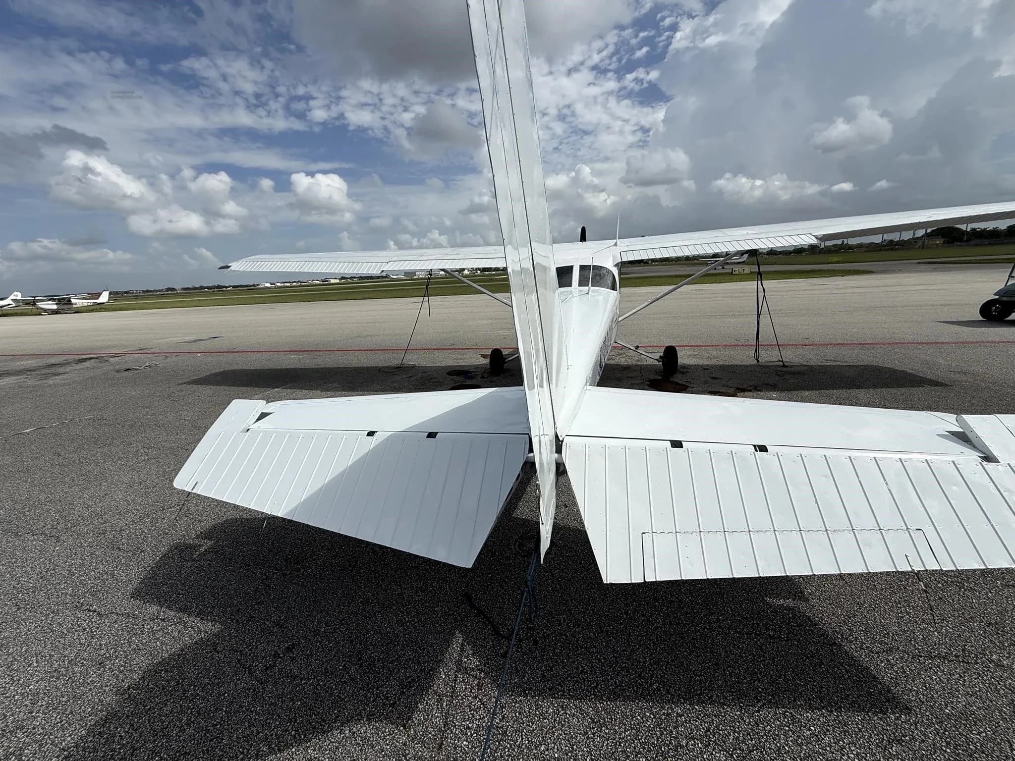 A direct rear view of the white Cessna 172 (N20818) showing the tail and horizontal stabilizers.