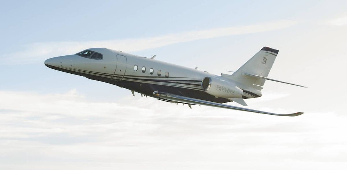 A Citation Latitude aircraft in flight against a blue sky.