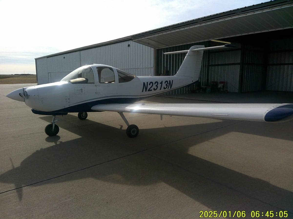 Side view of aircraft N2313N parked outside a hangar.